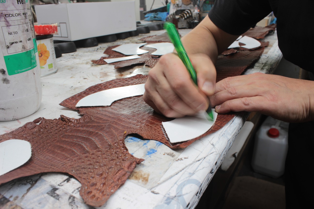 Hand cutting genuine caiman leather for custom shoes