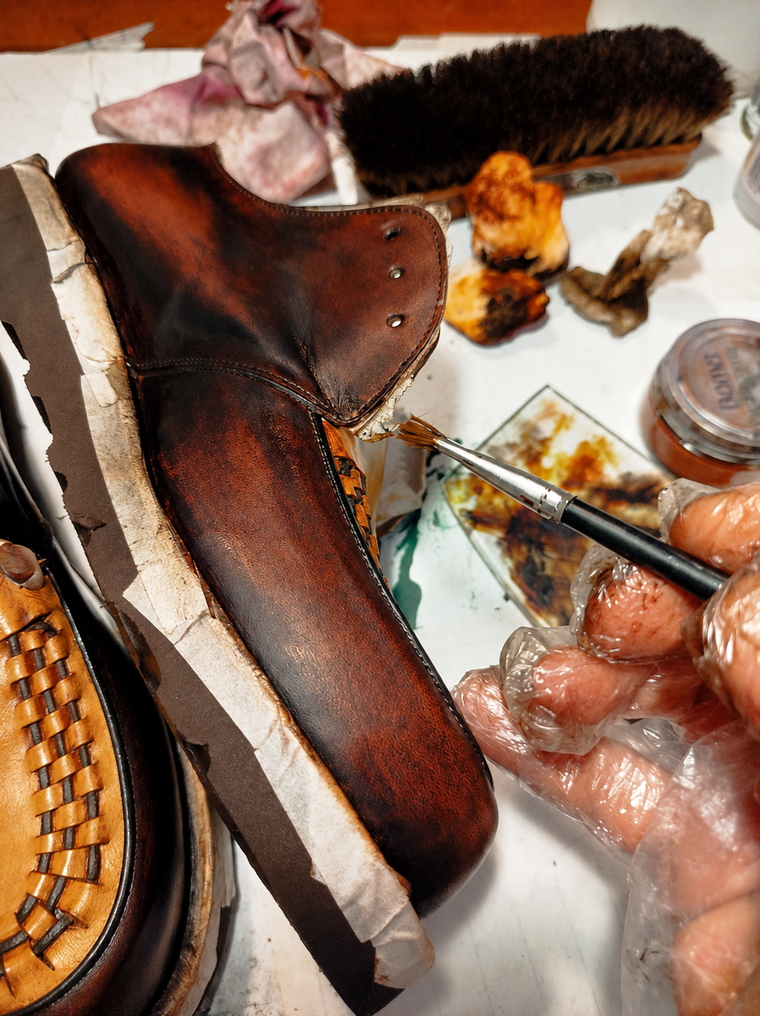 Patina and final leather finishing being applied by hand to a handmade shoe