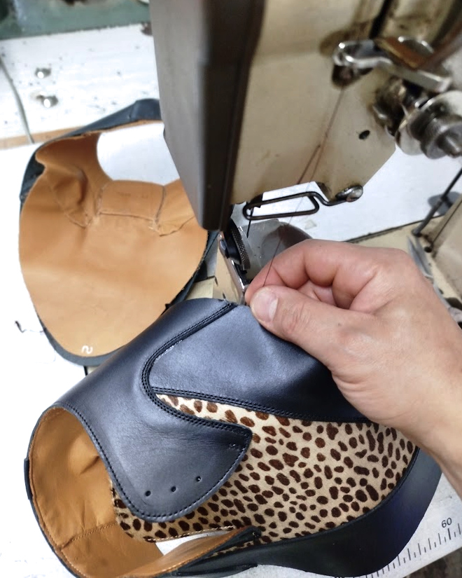 Leather upper being stitched by hand at the sewing machine during the making of a pair of creepers